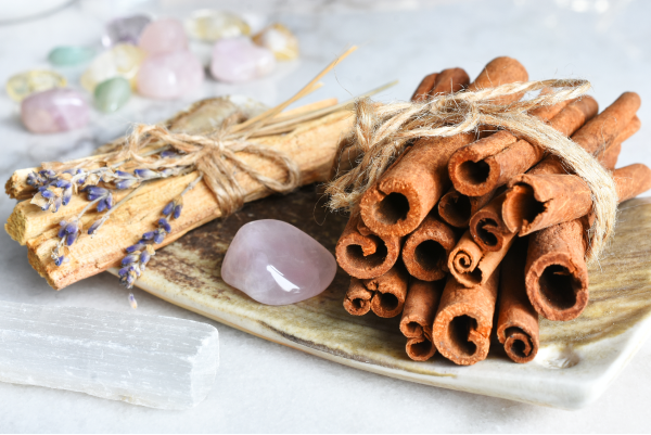 Cinnamon sticks and selenite crystal on a ceramic plate, surrounded by healing stones.